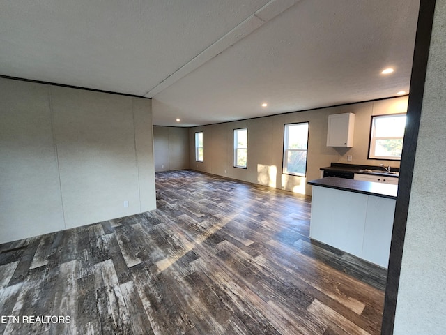 unfurnished living room with dark hardwood / wood-style flooring, a textured ceiling, and sink