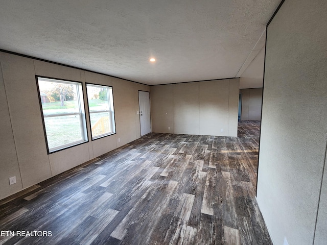 empty room featuring a textured ceiling and dark hardwood / wood-style floors