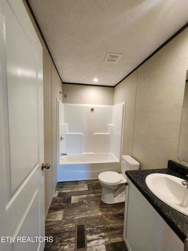 full bathroom featuring vanity, bathtub / shower combination, hardwood / wood-style flooring, toilet, and a textured ceiling