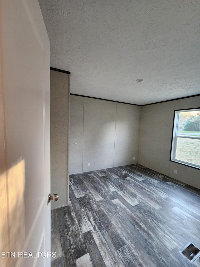 unfurnished room featuring dark hardwood / wood-style flooring and a textured ceiling