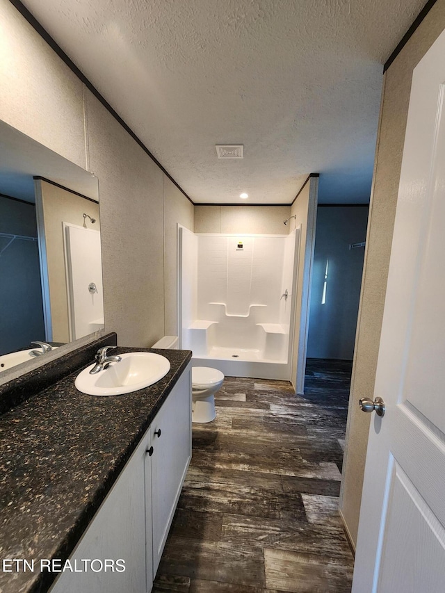 bathroom with walk in shower, a textured ceiling, toilet, vanity, and hardwood / wood-style flooring