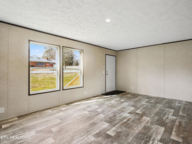 unfurnished room featuring light hardwood / wood-style flooring and a textured ceiling