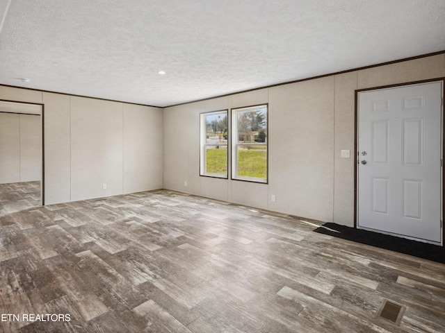 interior space with crown molding, wood-type flooring, and a textured ceiling