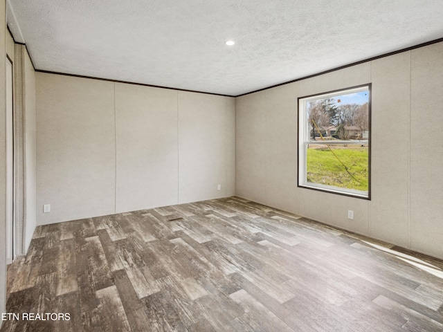 empty room featuring a textured ceiling, crown molding, and light hardwood / wood-style floors