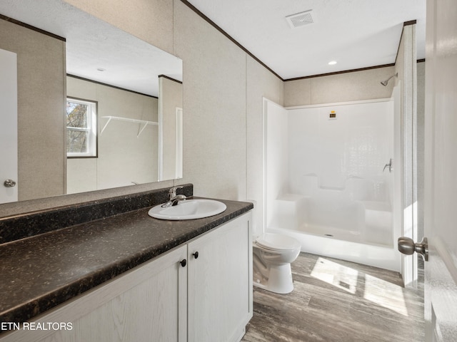 bathroom with wood-type flooring, vanity, a shower, toilet, and ornamental molding