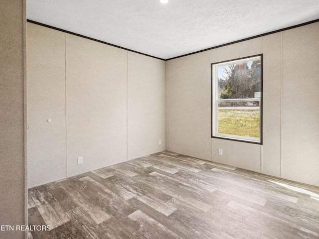 spare room with wood-type flooring, a textured ceiling, and ornamental molding