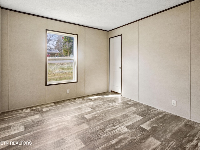 empty room with ornamental molding, a textured ceiling, and hardwood / wood-style floors