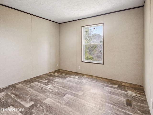 unfurnished room featuring a textured ceiling, hardwood / wood-style floors, and crown molding