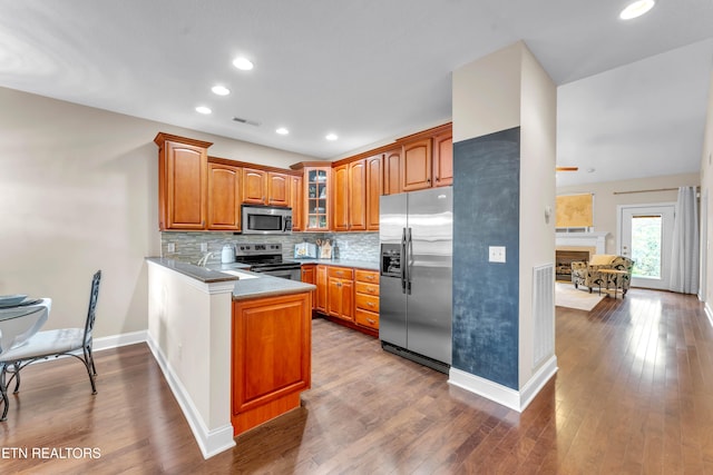 kitchen featuring kitchen peninsula, tasteful backsplash, stainless steel appliances, sink, and hardwood / wood-style floors