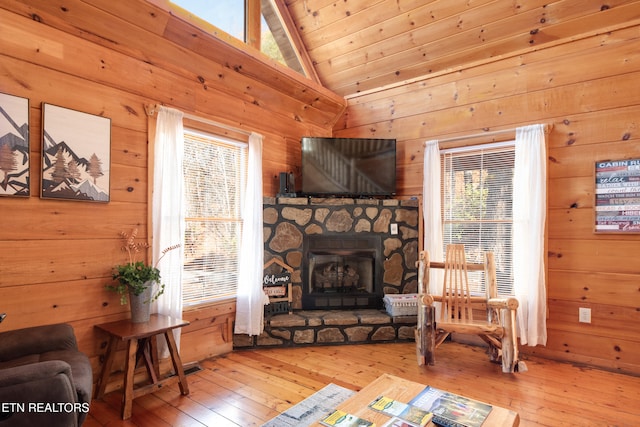 living room with a healthy amount of sunlight, wood-type flooring, wooden walls, and vaulted ceiling