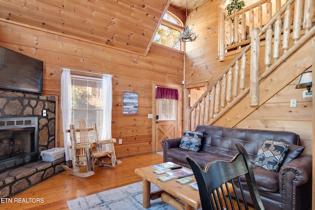 living room with wood walls, a towering ceiling, and hardwood / wood-style flooring