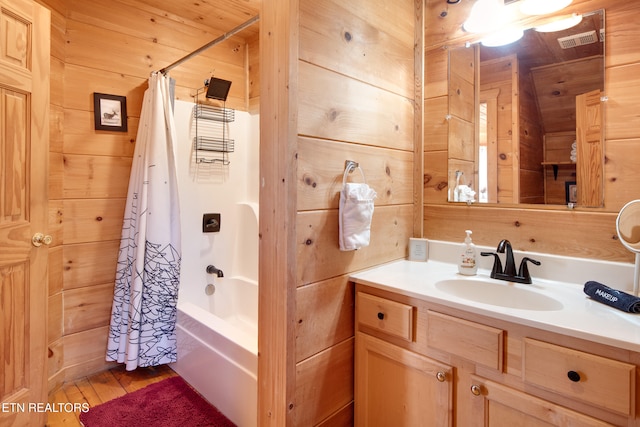 bathroom featuring vanity, hardwood / wood-style flooring, shower / bathtub combination with curtain, and wood walls