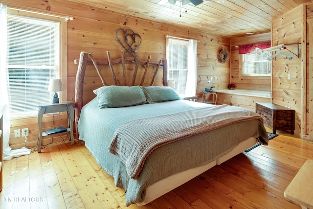 bedroom with wood ceiling, wood walls, ceiling fan, and light hardwood / wood-style floors