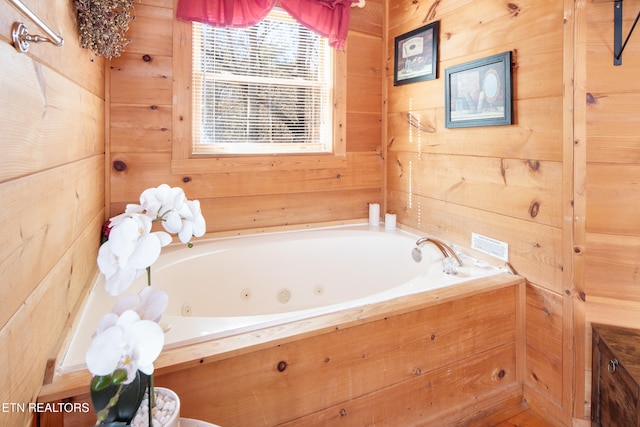 bathroom with a tub and wood walls