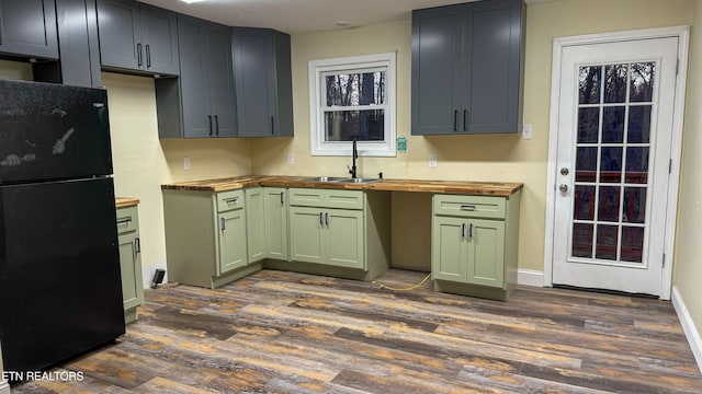 kitchen with butcher block countertops, black refrigerator, and dark hardwood / wood-style flooring