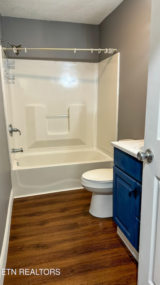 full bathroom featuring hardwood / wood-style floors, vanity, toilet, a textured ceiling, and tub / shower combination