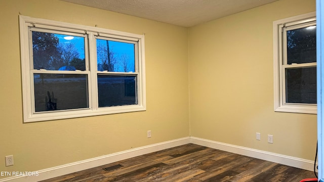 spare room with dark wood-type flooring and a textured ceiling