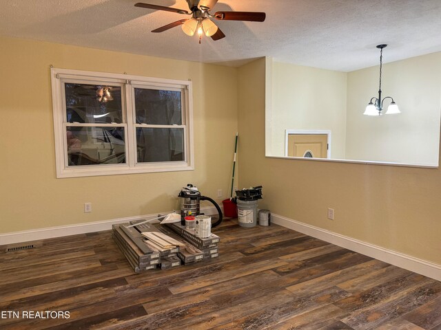 empty room featuring dark hardwood / wood-style flooring, ceiling fan with notable chandelier, and a textured ceiling