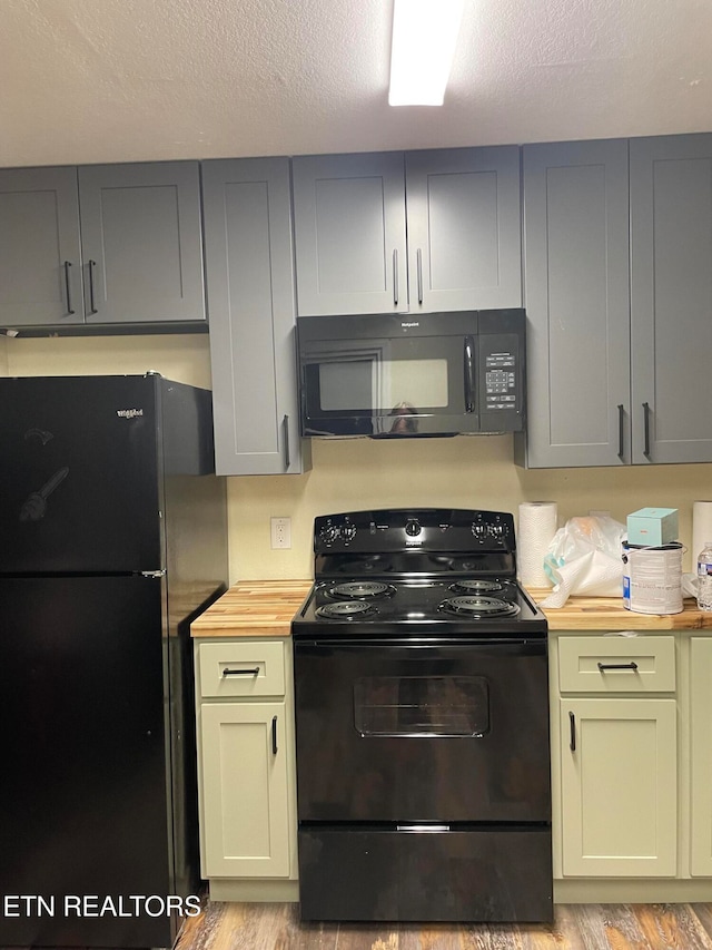 kitchen with light hardwood / wood-style flooring, black appliances, a textured ceiling, and wood counters