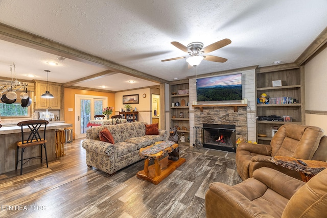 living room featuring beam ceiling, a stone fireplace, dark wood-type flooring, and a textured ceiling