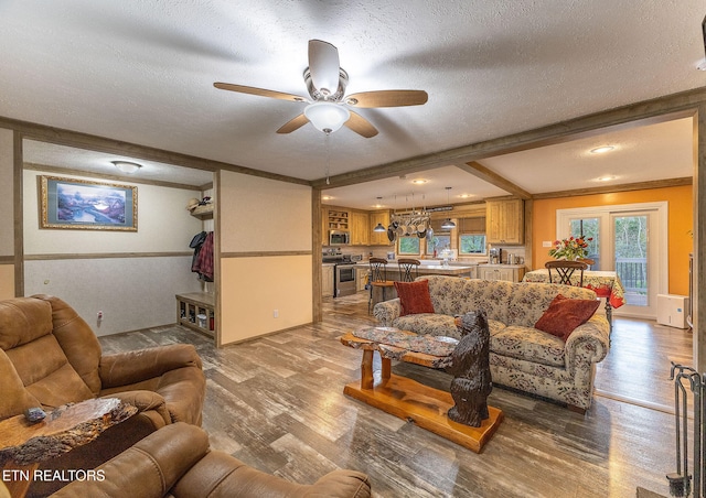 living room with beam ceiling, ceiling fan, light wood-type flooring, a textured ceiling, and ornamental molding