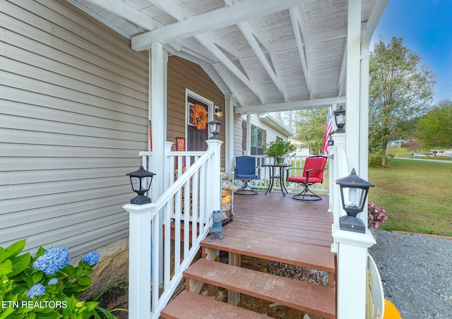 wooden deck featuring a porch and a yard