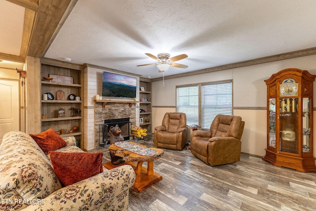 living room with hardwood / wood-style flooring, ceiling fan, ornamental molding, a fireplace, and a textured ceiling