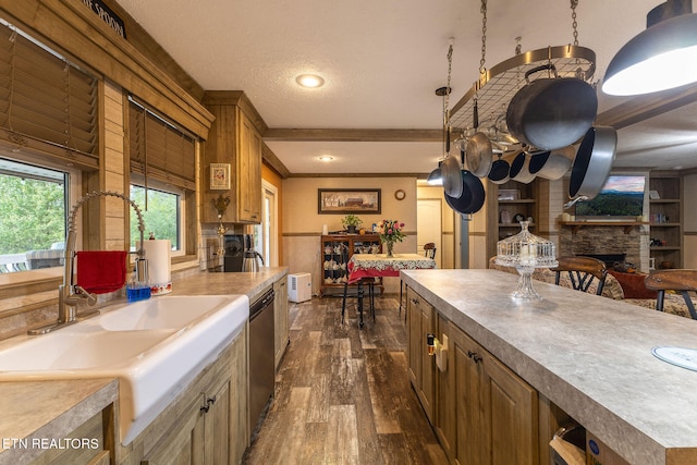 kitchen featuring dishwasher, a stone fireplace, dark hardwood / wood-style floors, crown molding, and a textured ceiling