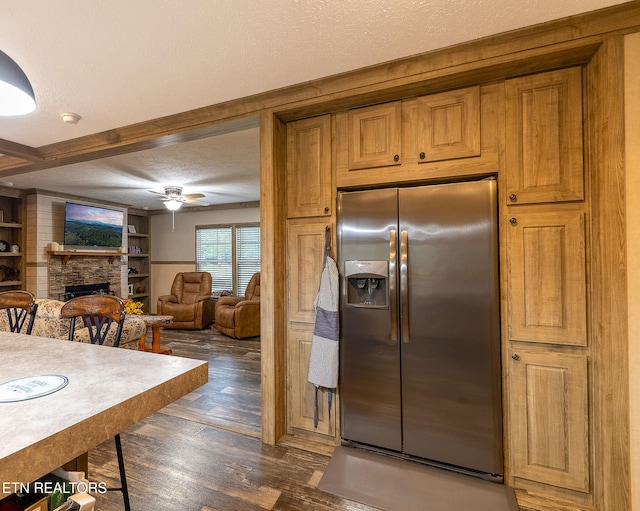 kitchen with dark hardwood / wood-style floors, stainless steel fridge, ceiling fan, a textured ceiling, and a fireplace