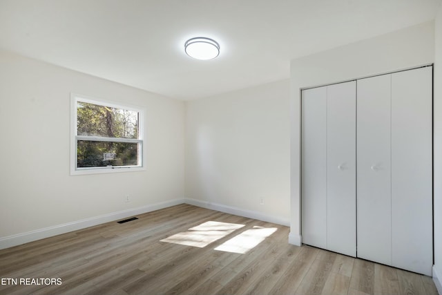 unfurnished bedroom with light hardwood / wood-style floors and a closet