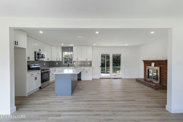 kitchen with a center island, stainless steel appliances, plenty of natural light, and light hardwood / wood-style flooring