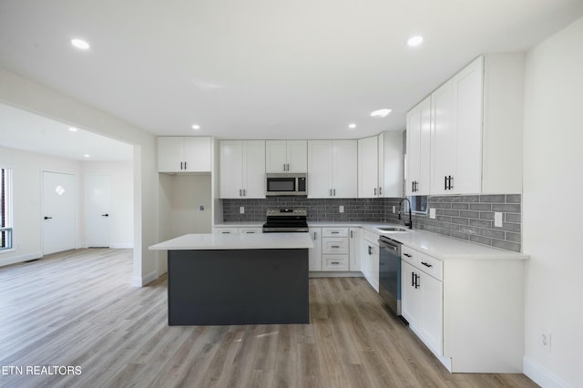 kitchen featuring white cabinets, sink, light hardwood / wood-style floors, appliances with stainless steel finishes, and a kitchen island