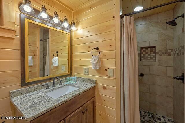 bathroom featuring a shower with curtain, vanity, wood ceiling, and wooden walls