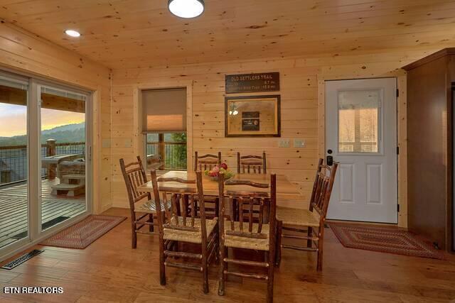 dining room featuring wood walls, wood ceiling, and light hardwood / wood-style flooring