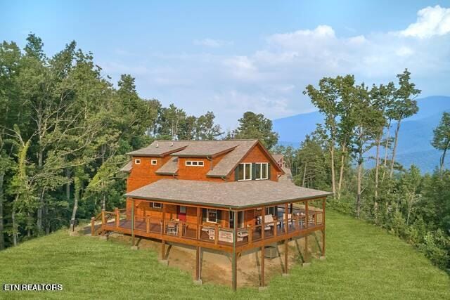 rear view of property featuring a yard and a wooden deck