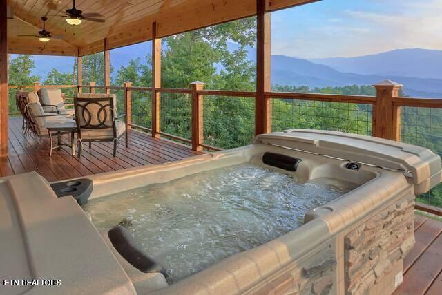 deck with a mountain view, ceiling fan, and a hot tub