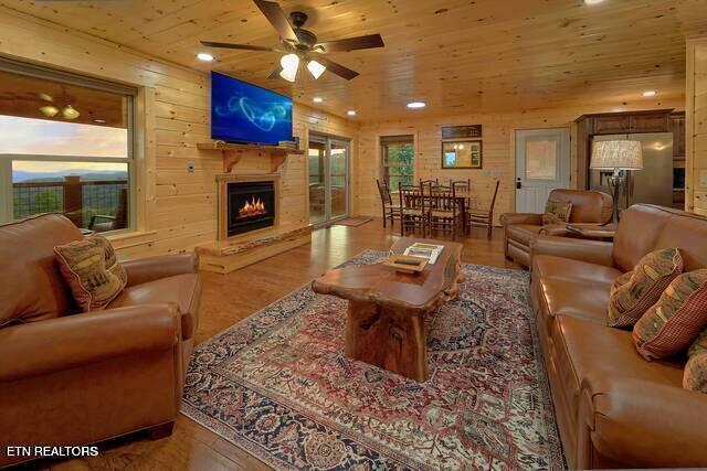 living room featuring hardwood / wood-style floors, ceiling fan, wood ceiling, and wooden walls