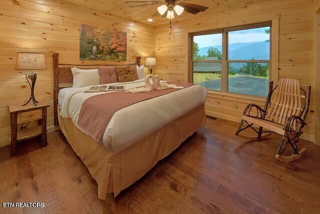 bedroom with hardwood / wood-style floors, ceiling fan, and wood walls