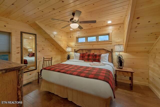 bedroom with wood-type flooring, vaulted ceiling, and wood walls