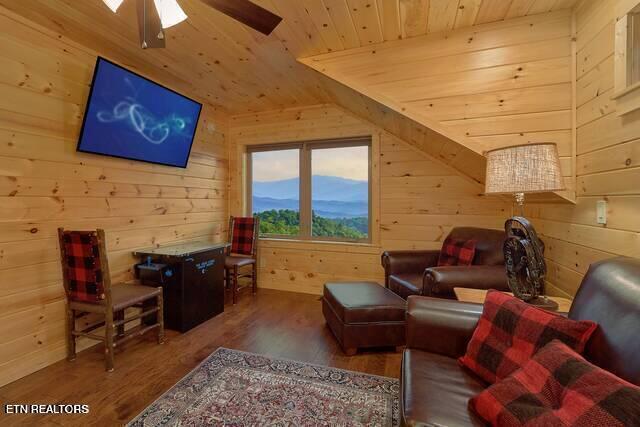 interior space with wood walls, vaulted ceiling, ceiling fan, dark hardwood / wood-style flooring, and wood ceiling