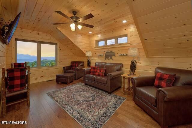 living room with vaulted ceiling, ceiling fan, wooden walls, hardwood / wood-style flooring, and wooden ceiling