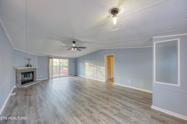 unfurnished living room with ceiling fan, a textured ceiling, lofted ceiling, a fireplace, and hardwood / wood-style flooring