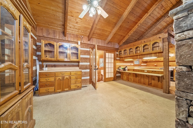 carpeted office space with wood walls, wooden ceiling, french doors, lofted ceiling with beams, and ceiling fan