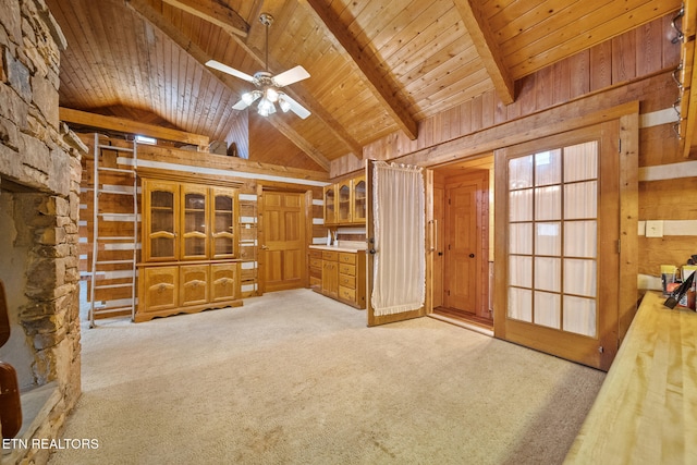 unfurnished living room with light carpet, beam ceiling, wooden walls, and wood ceiling