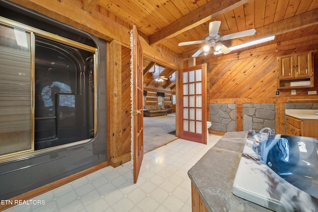 interior space featuring beam ceiling, ceiling fan, a washtub, wooden ceiling, and wooden walls