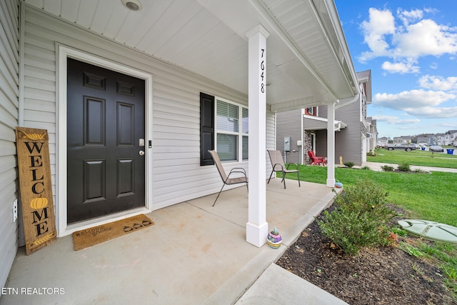 doorway to property with a porch and a yard