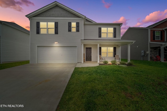 view of property featuring a lawn, covered porch, and a garage