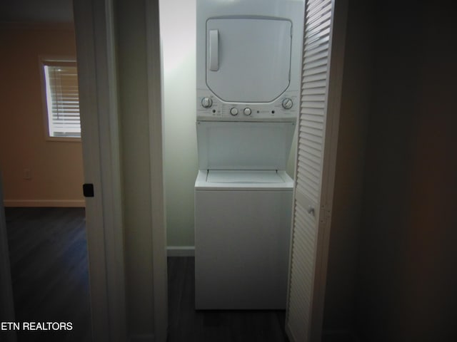 laundry room with dark hardwood / wood-style floors and stacked washer / dryer