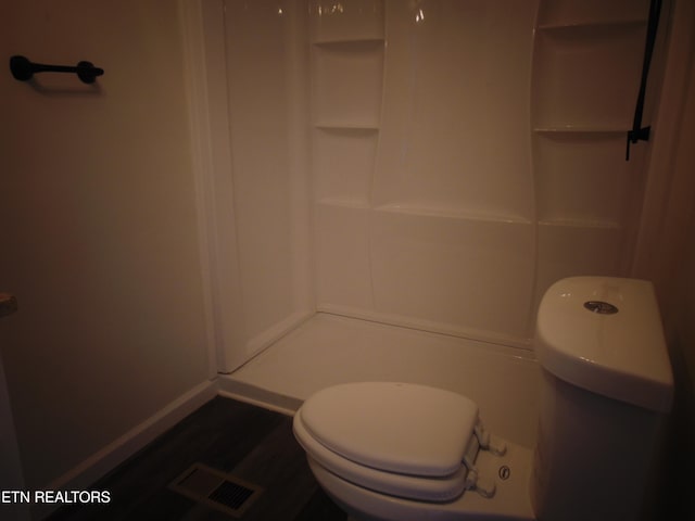 bathroom featuring a shower, hardwood / wood-style flooring, and toilet