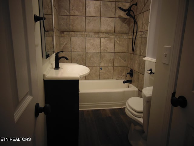 full bathroom with hardwood / wood-style floors, vanity, tiled shower / bath combo, and toilet